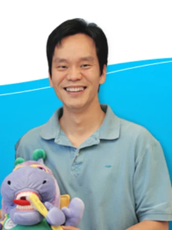 Dr. Alex Wong smiling and holding Mr. Monkey, the practice's plush helper